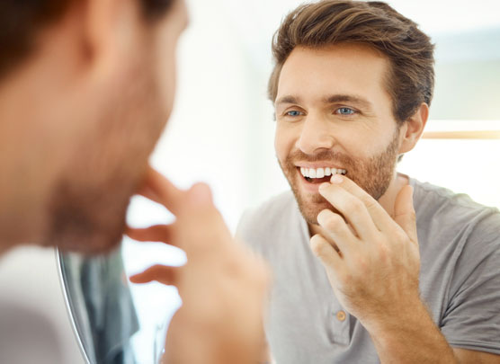 Man examining gums in mirror