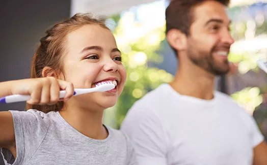 Father and daughter brushing teeth